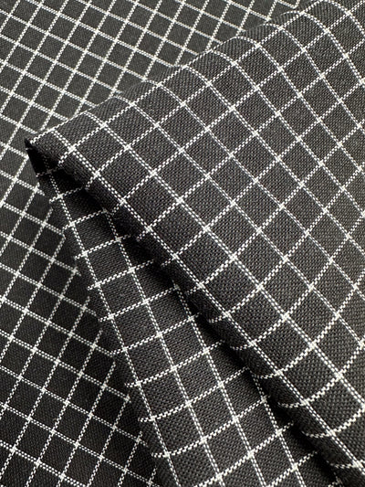 Close-up of layered Linen Rayon Grid - Black - 145cm by Super Cheap Fabrics, ideal for garment creations or home decor items. The woven texture and detail are evident, with uniform grids forming a neat, linear design. The layers add depth to the image.