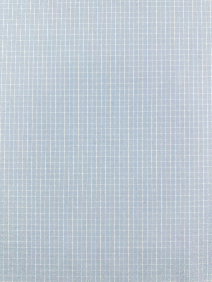 A seamless pattern of light blue graph paper with a grid of thin white lines forming small squares. The grid lines are evenly spaced and consistent, creating a uniform and repetitive geometric design perfect for high-quality printed linen in home decor items or garment creations like the Linen Rayon Grid - Baby Blue - 145cm from Super Cheap Fabrics.