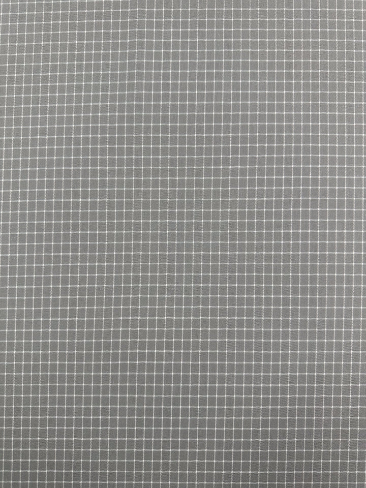 A close-up image showcasing a grey grid pattern with small, evenly spaced white lines forming squares on a textured, high-quality printed linen fabric. The design is uniform and symmetric, creating a geometric and orderly appearance, making it ideal for versatile home decor items such as the Linen Rayon Grid - Grey - 145cm from Super Cheap Fabrics.