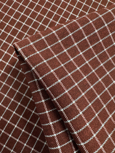A close-up view of Linen Rayon Grid - Rosewood - 145cm from Super Cheap Fabrics. The home decor fabric features evenly spaced, small white squares, giving it a checked appearance.