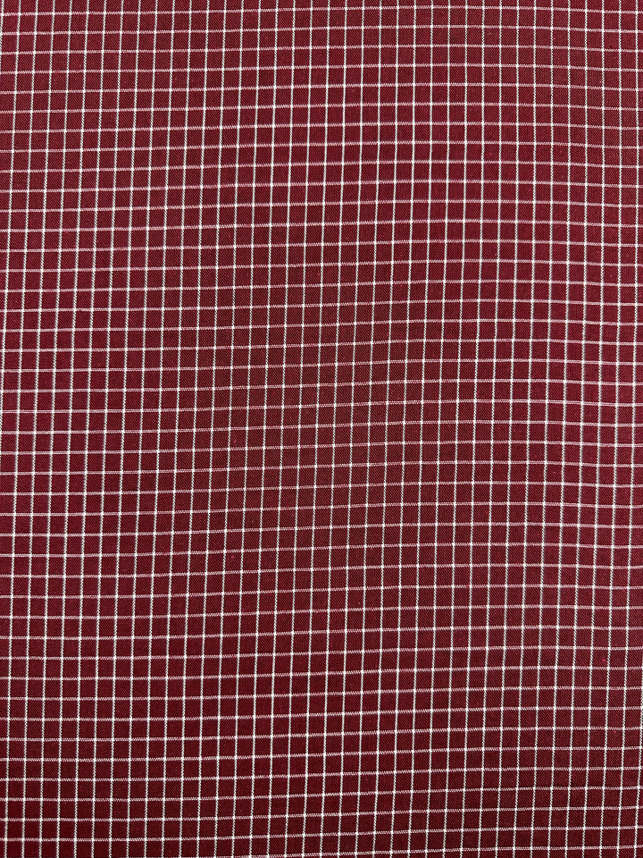 A close-up of Super Cheap Fabrics' Linen Rayon Grid - Cabernet - 145cm, featuring a white, grid-like checkered pattern. The small and evenly spaced squares created by the white lines lend the versatile material a neatly structured appearance, perfect for home decor.