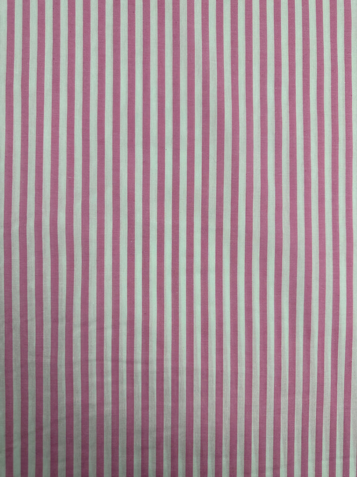 A lightweight fabric featuring a pattern of vertical pink and white stripes. The stripes are evenly spaced and run parallel from top to bottom. Made from 100% cotton, the colors are consistent across the entire material, ensuring a uniform appearance. This is the Cotton Lawn - Pink Stripe - 150cm by Super Cheap Fabrics.