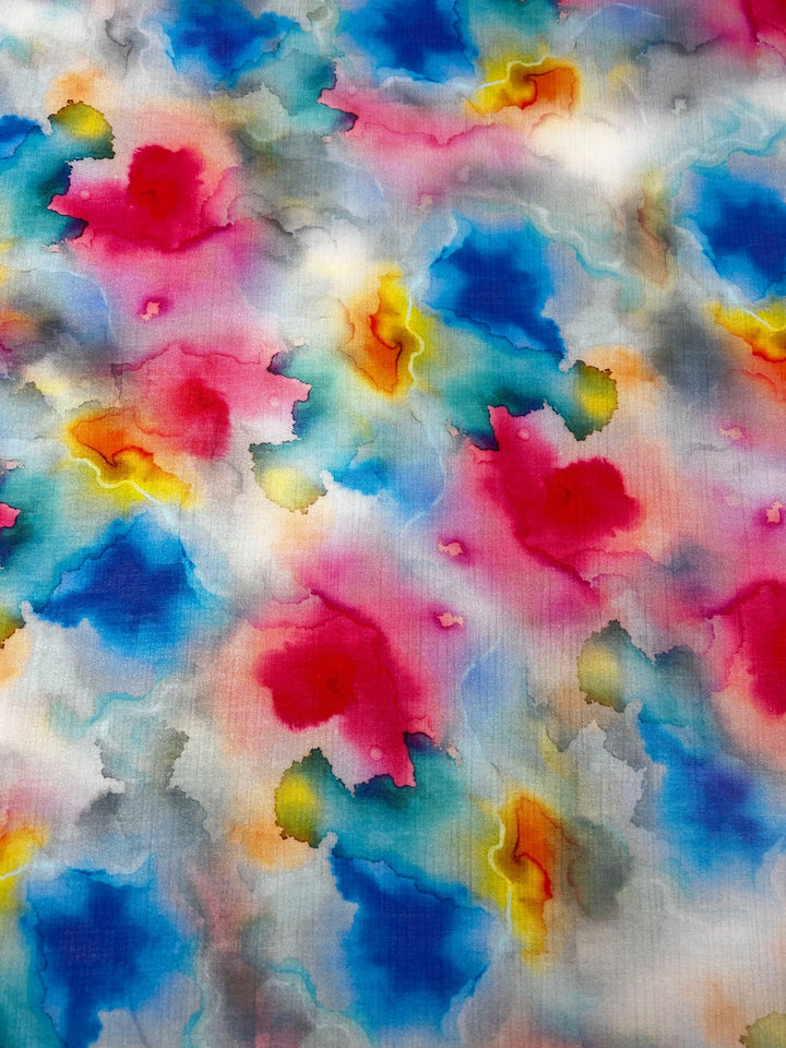 Experience the vibrant and dynamic abstract design of "Designer Cotton - Venus - 150cm" by Super Cheap Fabrics, featuring a watercolor pattern with splashes of bright blues, pinks, yellows, and reds. The colors blend seamlessly to create a textured appearance that is perfect for luxury sewing projects requiring high-quality designer cotton fabrics.