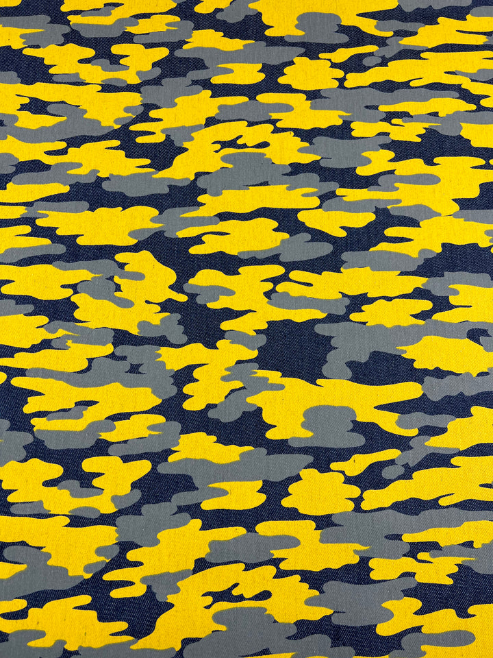 A pattern featuring a camouflage design with irregular shapes in shades of yellow, gray, and dark blue on medium to heavy weight 100% cotton fabric. The shapes are randomly distributed across the surface, creating a textured and dynamic visual effect. Cold wash recommended.

Product: **Printed Denim - Camouflage - 145cm**

Brand: **Super Cheap Fabrics**