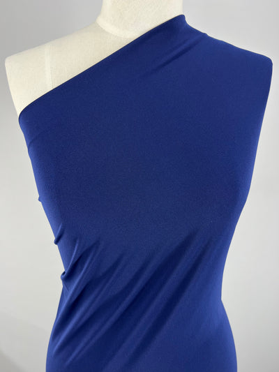 A mannequin torso displays a one-shoulder, Beacon Blue dress. The elegant gown, crafted from medium weight fabric by Super Cheap Fabrics, features a smooth, fitted design and drapes gracefully over the body, highlighting a minimalist yet sophisticated fashion style. The background is plain and grey.