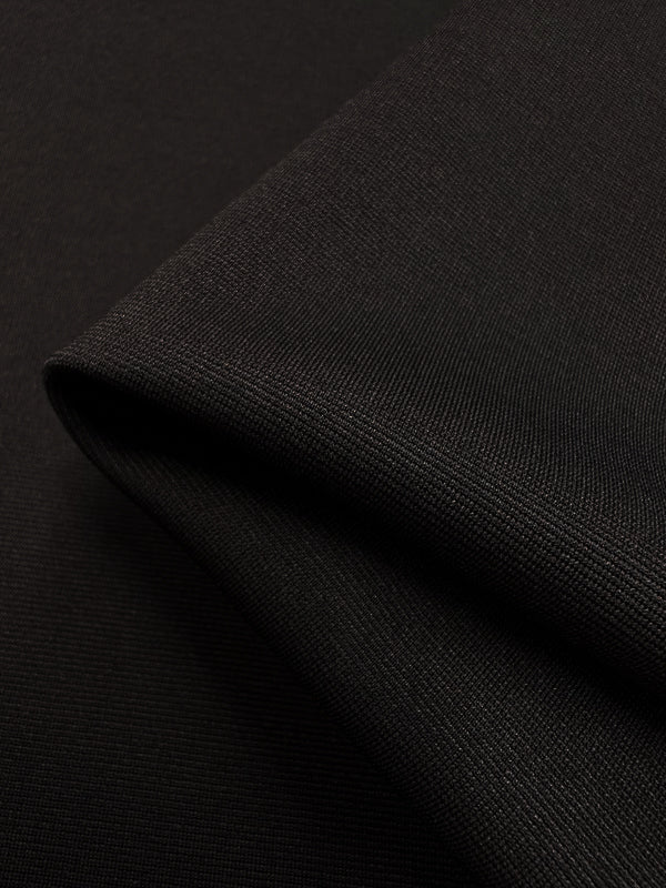 Close-up of folded black Ponte - French Toast knit fabric from Super Cheap Fabrics, showcasing its smooth texture and fine weave. The fabric exhibits a slight gloss, with subtle highlights where the light hits it. The folded edge creates a gentle shadow, adding depth to the image.