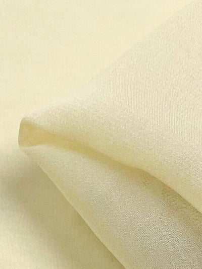 Close-up image of folded Silk Georgette - Butter from Super Cheap Fabrics, showcasing its smooth and slightly textured surface. The gentle folds create soft shadows, highlighting the fabric's subtle sheen and fine weave—perfect for spring and summer outfits.