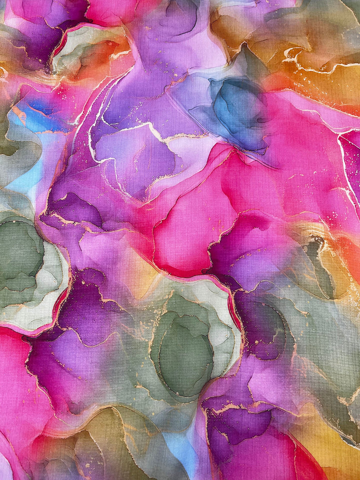 The Designer Cotton - Adelina - 150cm from Super Cheap Fabrics showcases a vibrant abstract design with swirls of pink, purple, green, and gold. The colors seamlessly blend and overlap to create fluid shapes and textures, while the thin gold lines throughout the composition add a shimmering effect.