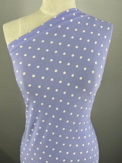 A dress form is draped with Printed Lycra - Lavender Polka - 150cm from Super Cheap Fabrics. The form is set against a plain grey background. The smooth fabric fits snugly around the torso, highlighting its design.