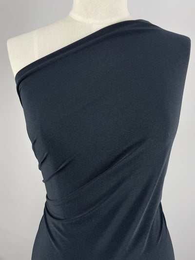 A close-up of a mannequin draped in ITY Knit - Navy - 150cm fabric by Super Cheap Fabrics, elegantly gathered to create a smooth, one-shoulder look. The medium weight fabric showcases the texture and flow of the material against a simple, minimalist background.