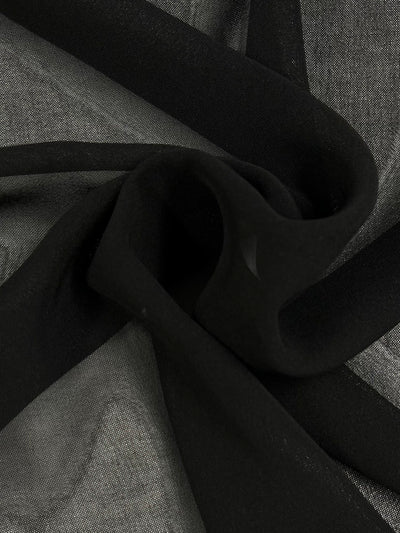 Close-up of a folded black and gray Plain Weave Single Georgette - Black - 150cm by Super Cheap Fabrics. The lightweight fabric is draped and bunched, creating a sense of depth and texture with a smooth surface. Light shadows enhance the contrast between dark and lighter areas, offering a detailed view of the material.