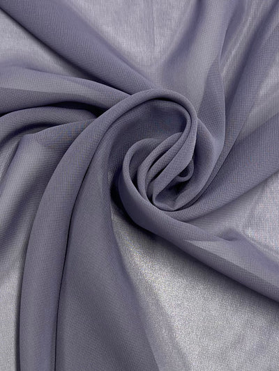 A close-up of a piece of Hi-Multi Chiffon - Gray Ridge - 150cm by Super Cheap Fabrics is shown, loosely gathered and twisted into a soft swirl in the center. The texture appears light and delicate, with a gentle drape highlighting the fabric's flow and smooth surface, perfect for creating floaty tops.
