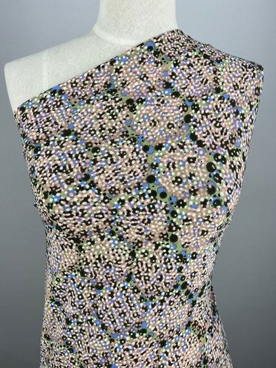A mannequin is wearing a sleeveless, asymmetrical top crafted from medium-weight polyester/spandex fabric, featuring a multicolored polka dot pattern. The top has one shoulder covered while the other is bare, against a plain gray background. The fabric used for this top is Crepe Printed Lycra - Connect The Dots - 150cm by Super Cheap Fabrics.